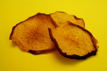 Naklejka premium three dried peach chips lie on a yellow background. healthy homemade food. peach