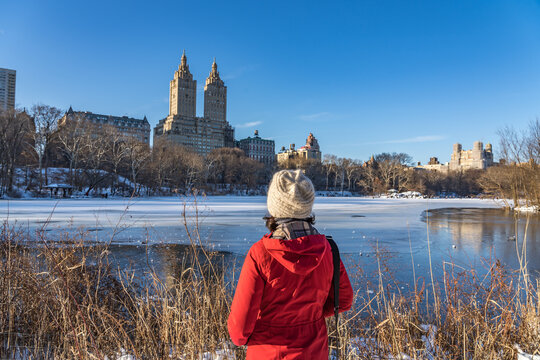 Woman at Central Park in the ice-cold winter facing the beautiful view of New York City historical building in upper westside.