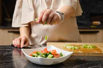 Obraz na płótnie Canvas Closeup of hand of woman dropping a sliced celery into a bowl