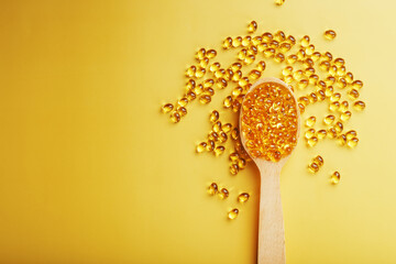 Vitamin D3 in a wooden spoon on a bright yellow background