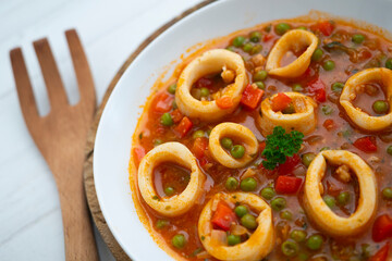 Squid stew, red pepper and peas. Spanish traditional tapas.