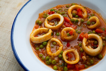 Squid stew, red pepper and peas. Spanish traditional tapas.