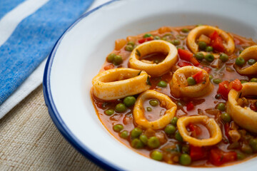Squid stew, red pepper and peas. Spanish traditional tapas.