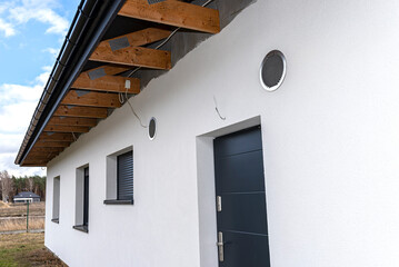 Air intake and exhaust in the wall of a single family house for mechanical ventilation with heat recovery, secured with a metal grill with mesh.