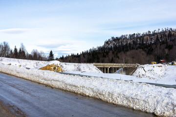 Winter road in the mountains, traveling through snowy mountainous terrain on a sunny frosty day.