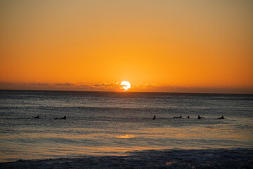 amazing sunrise behind of surfers riding some waves with great colours