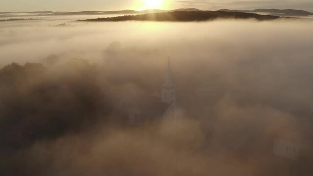 Golden hour sunset setting beyond church in dense cloud 