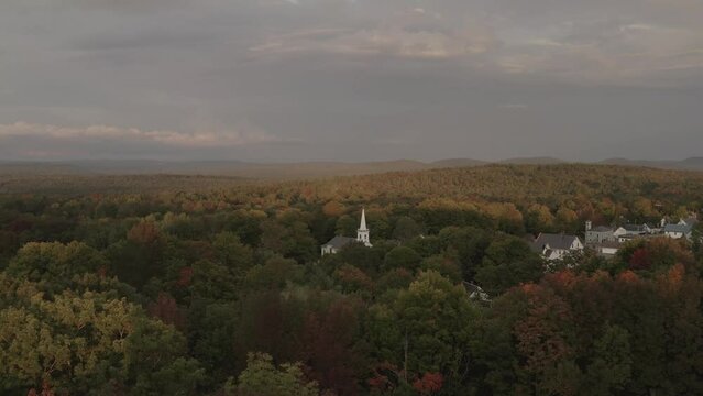Beautiful aerial Monson Town, Maine vast Autumn colored woodland surrounding church 