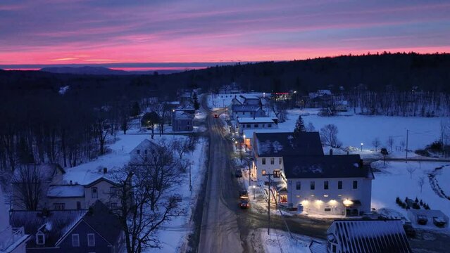Vibrant sunrise over Monson Town, Maine covered in snow aerial shot 