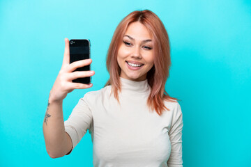 Young Russian woman isolated on blue background making a selfie