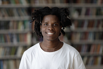 Head shot portrait of pleasant handsome happy African American male student with curly hairstyle...
