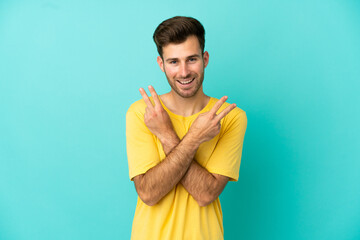 Young caucasian handsome man isolated on blue background smiling and showing victory sign