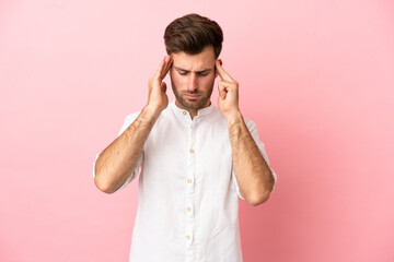 Young caucasian handsome man isolated on pink background with headache