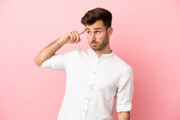 Young caucasian handsome man isolated on pink background making the gesture of madness putting finger on the head