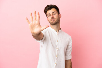 Young caucasian handsome man isolated on pink background counting five with fingers