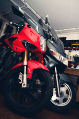 Motocykl i skuter stojący w warsztacie. W tle garaż, narzędzia.