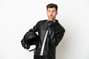 Young caucasian man with a motorcycle helmet isolated on white background looking up while smiling