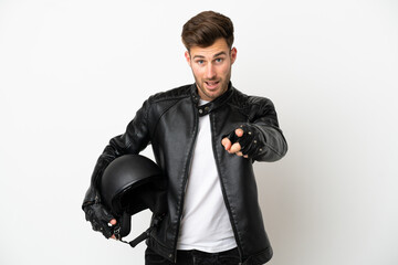 Young caucasian man with a motorcycle helmet isolated on white background surprised and pointing front