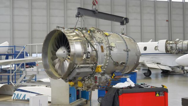 Aircraft Jet Engine Turbofan Suspended on Crane in Maintenance Shop.