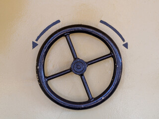 Black valve on the door of the ship with arrows and the inscription 