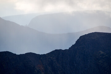 Mountain peaks in the clouds. A chain of gray mountains in the backlight. Khibiny
