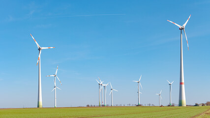 Panoramic view over beautiful farm landscape with early spring agriculture field, wind turbines to...
