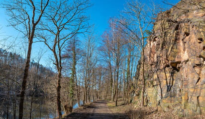 Fototapeta na wymiar View over magical deciduous forest and hills landscape at riverside of Zschopau river near Mittweida town, Saxony, Germany, at warm sunset and blue sky.
