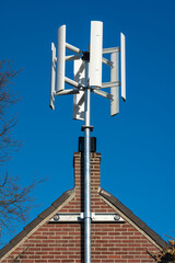 Small vertical axis wind turbine for homes, close up of small power generator mounted on the house...