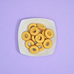 Sweet cookies in white plate on pastel purple background. Flat lay food concept