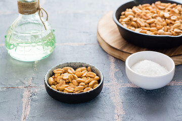Roasted peanuts in a bowl and in a frying pan, a bowl with salt on the table. Plant source of protein. Vegetarian food