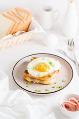 Homemade sandwich - croque madame on a plate on a light table. Vertical view