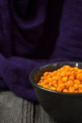 orange sea buckthorn berries on wooden table. copy space