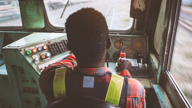An African train driver is driving a public train on the railway