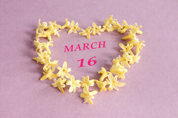 Calendar for March 16: number 16, the name of the month of March in English in a heart made of yellow hyacinth flowers, pastel background, top view