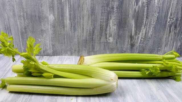 Bundles of fresh celery lie on a wooden table