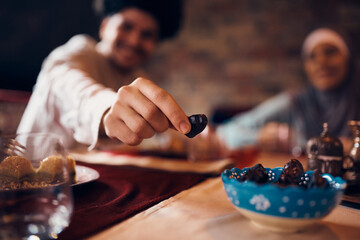 Close-up of Middle Eastern man eats date during dessert at home.