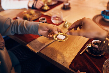 Close-up of Muslim women eat rahat lokum for dessert while drinking coffee at home.