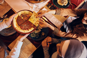 Above view of unrecognizable Muslim people having Turkish pizza for lunch.