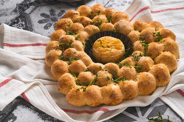 Roasted camembert cheese and homemade bread heart shaped and thyme on rustic background. French cheese. Concept of romantic love for Valentines Day. Top view, copy space.