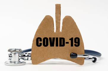 On a white surface are a stethoscope and a cardboard figure of a lung with the inscription -...