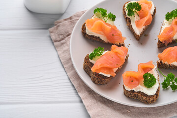 Mini sandwiches with salmon, curd cheese, parsley and rye bread in form of hearts. Valentine's day homemade creative food. Love breakfast design. Selective focus and copy space