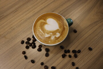 green cup of coffee and beans on wooden table