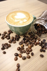 green cup of coffee and beans on wooden table
