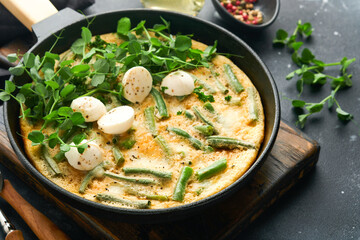 Frittata. Omelet with spinach and green beans, healthy food in black frying pan on dark old rustic background. Healthy breakfast delicious. Top view flat lay. Copy space.