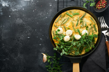 Frittata. Omelet with spinach and green beans, healthy food in black frying pan on dark old rustic background. Healthy breakfast delicious. Top view flat lay. Copy space.
