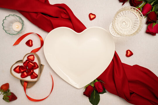 Heart-shaped plate and Valentines Day decorations on table