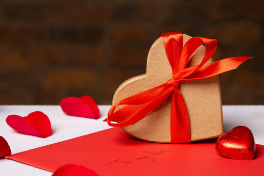 Heart-shaped gift box and Valentines Day decorations on table