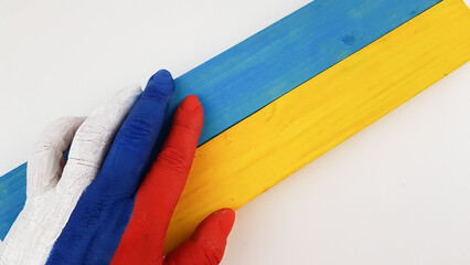 the hand is painted in the colors of the Russian flag and holds the colors of the Ukrainian flag. place for text