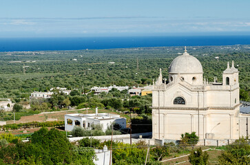 View on a white building church and green landscape and blue sea in Apulia in Italy. Old...