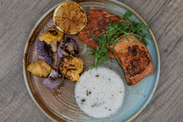 Hearty dinner plate of grilled salmon, white rice, and colorful cauliflower on a plate